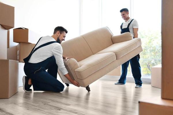Professional movers carefully moving a sofa inside a home